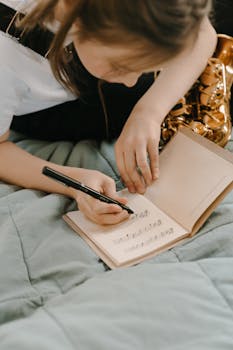 A young musician writes music notes in a notebook beside a saxophone, practicing creativity.